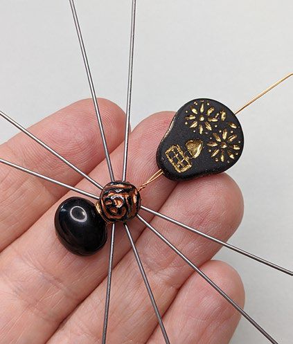 Large flat black skull bead is threaded onto both wires, narrow side first.